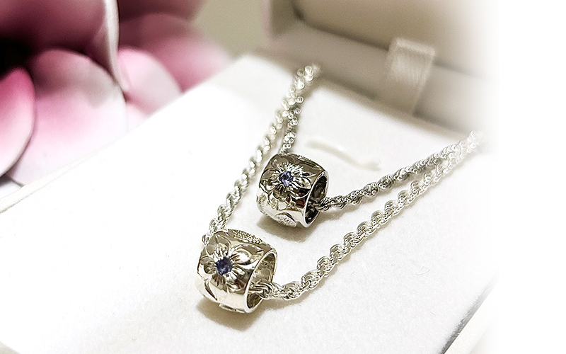 プルメリアの中心にはご結婚記念日の月のお石「タンザナイト」をセット。
 
美しく神秘的な青の色味は角度によって色の濃淡も変わり、どの角度からも華やかさのあるとても魅力的なペンダントとなりました。
 
幸せを招く“波”、大切な人や愛を意味する“プルメリア”、波と波とを結ぶ“リーフ”のデザインを組み合わせることで、お二人の夫婦生活がより愛と希望に満ちた未来へ導く、特別感溢れるアニバーサリーペアジュエリーとなりました。
