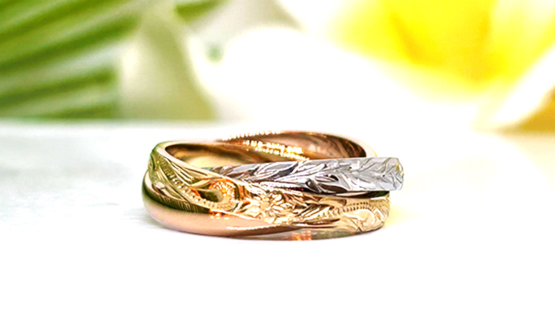 定年退職の記念として、奥様とお嬢様3人へそれぞれお好きなリングを贈られることになり、MAILE名古屋栄店へご来店くださった松浦様。
奥様は以前から気になっていた3つの指輪が連なった「トリニティリング」をお選びいただきました。
ブラウンゴールド、ピンクゴールド、プラチナの3色は華やかさがありながらも肌に馴染む上品な色味で、洗練された雰囲気の奥様に大変お似合いでございました。
ハワイ伝統の手彫りデザインはお嬢様方とご相談頂きながら、波のヘリテイジと葉のマイレリーフに。
ご両親からお嬢様へ‟永遠に受け継がれる想い“、そしてご家族皆様の‟聖なる繋がり”の意味が込められた素敵なデザインとなりました。
