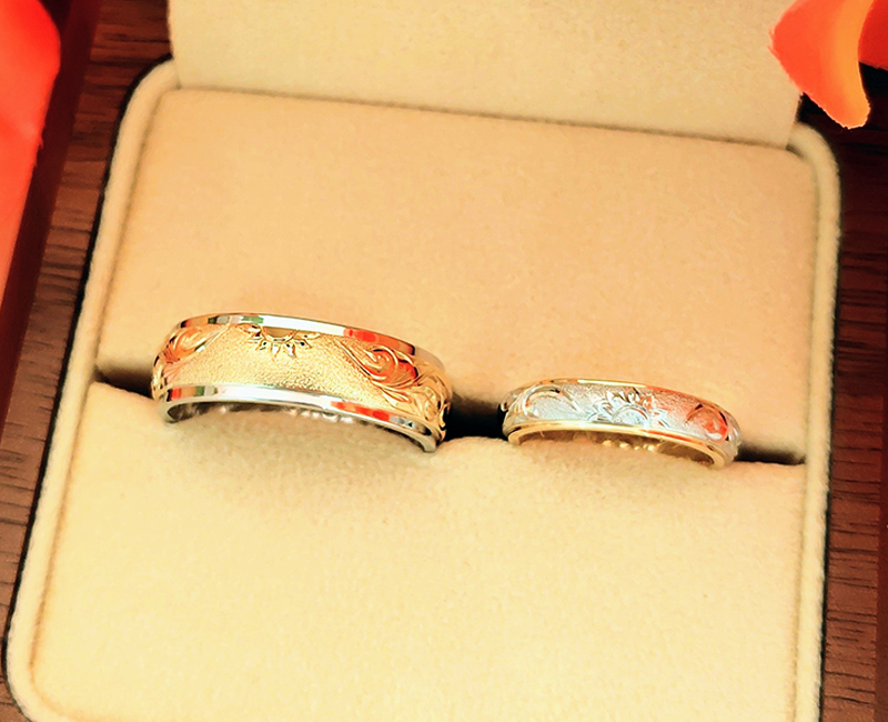 おふたりにお選びいただいた指輪は、白銀色に輝く上品で気品ある「プラチナ950」と、金本来の輝きと華やかな黄色を持つ「K18イエローゴールド」の2種類の地金の素材を組み合わせ、更に表面と内側の両面に手彫りを刻んだ『両面彫りツートーンリング』。
&nbsp;
おふたりでベースとトップの地金を入れ替えて、ペア感を出しつつそれぞれのお好みに沿う組み合わせに。
&nbsp;
リング幅はお手元とのバランス等も考慮されながら、4mm幅と7mm幅でそれぞれお選びいただきました。
