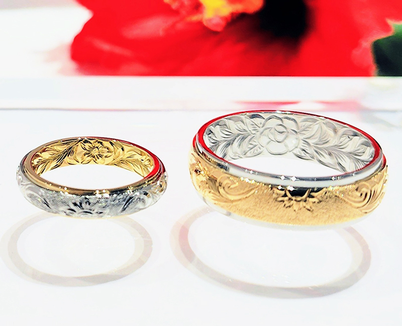 手彫りは、「マイレレイ」をメインのデザインとして。 内側には、K様は魅力を高める魔除けの花の「プルメリア」、N様はハワイ語で〈天国のバラ〉を意味し、マウイ島の公式島花で愛と美を象徴する花「ロケラニ」をポイント彫りとして。
&nbsp;
お二人とも中心のお花から、神々が宿るとされる神聖な「マイレ」の葉が広がり、葉の終わりの部分にはそれぞれ「プルメリア」、ハワイ州の州花で〈幸せな未来〉を象徴する「ハイビスカス」、〈海の守り神のウミガメ〉「シータートル」が、ハワイの熟練の彫師の手によって刻まれました。
&nbsp;
おふたりの想いとハワイの大自然をリングの両面にたっぷり詰め込んだ、世界にふたつとないスペシャルなハワイアンマリッジリングに仕上がりました。
